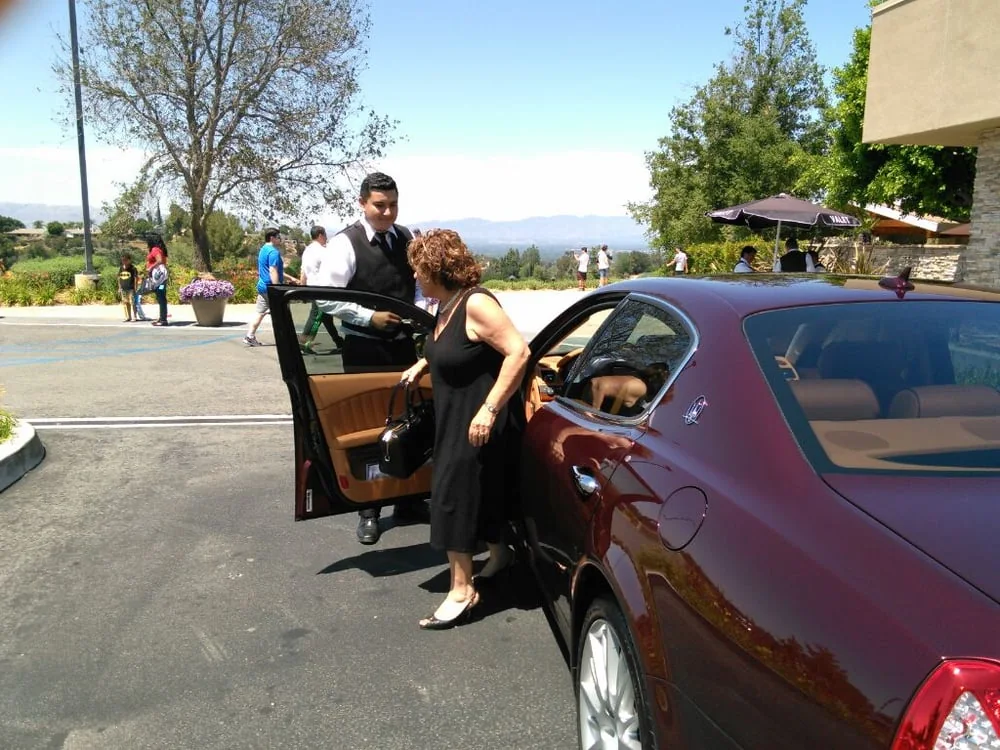 A&A Parking Services valet attendant opening the car door for an arriving guest at a hillside venue in Los Angeles County