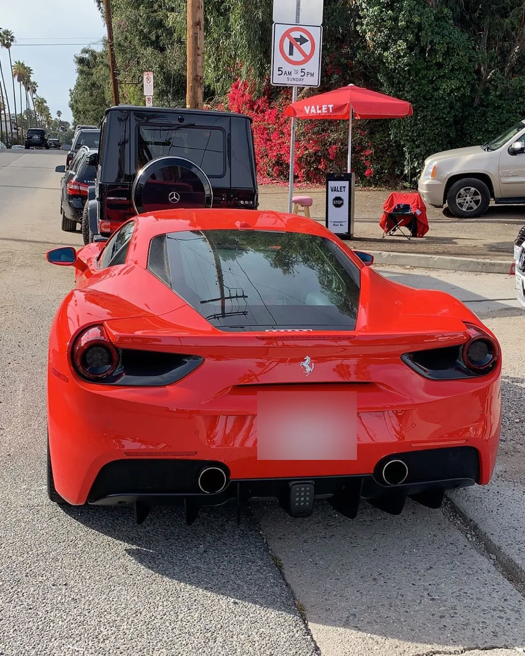 Red Ferrari 488 at an A&A Parking Services valet stand with the branded red VALET umbrella in Los Angeles County